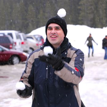 Happy man juggling snowballs in winter park