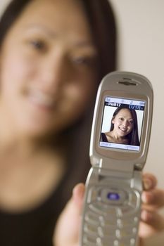 Young asian woman showing the display from a cell phone camera