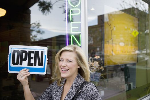 A happy owner holding up an Open sign in front of her new business