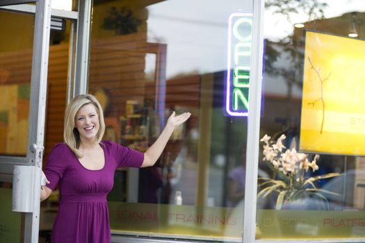 A happy business owner opening her shop door