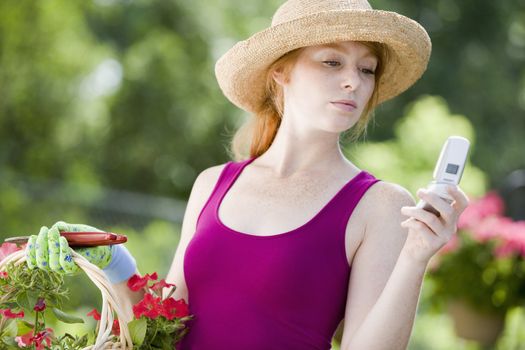 Pretty young woman gardener looking at her cell phone