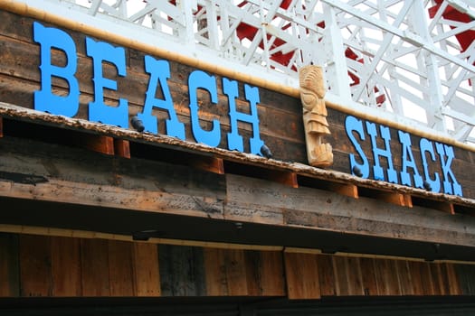 Close up of a beach shack sign and a totem pole.
