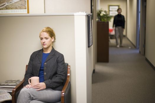 Young woman waiting in office lobby holding coffee cup