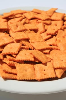 Close up of orange cheese crackers on a plate.
