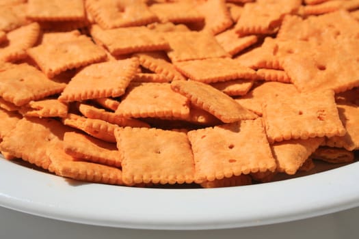 Close up of orange cheese crackers on a plate.
