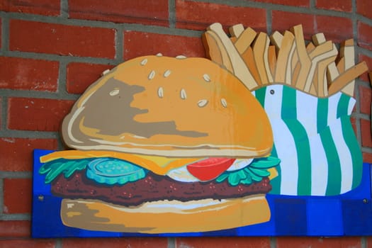 Close up of a cheeseburger and french fries sign.
