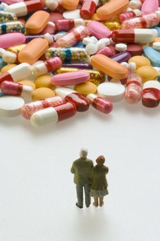 Miniature couple standing in front of capsules and pills