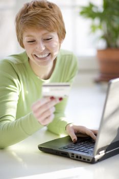 Smiling young woman shopping online with credit card and laptop computer