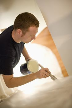 Young man concentrates painting stairway walls