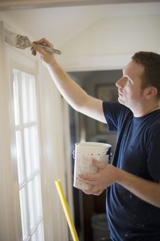 Young man painting door trim inside a house