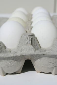 Close up of chicken eggs in a carton.
