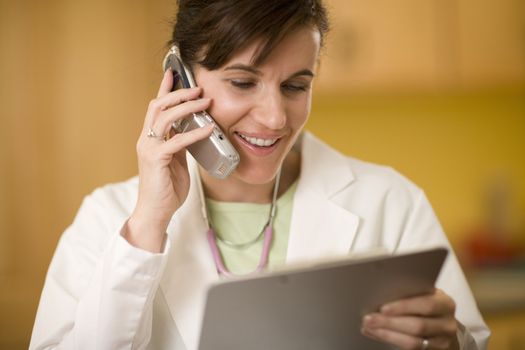 Woman doctor talking on cell phone and looking at a medical chart