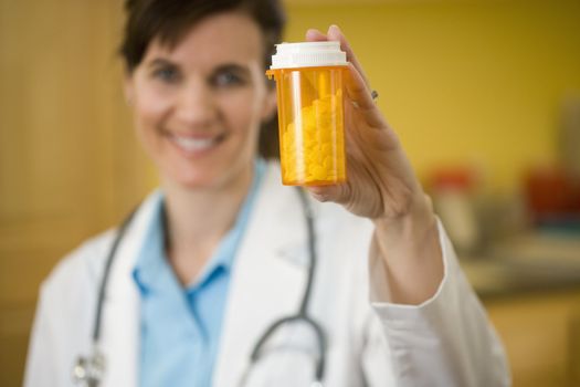 Female Physician holding bottle of pills up to camera, focus on pills