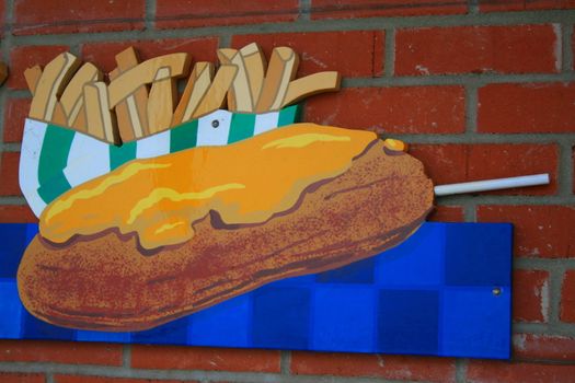 Close up of a corn dog and french fries sign.
