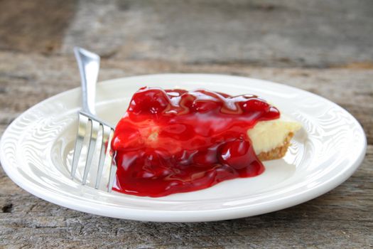 Cherry cheesecake on a white plate with a fork.