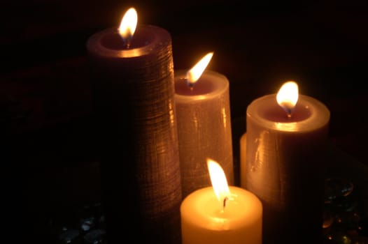four lit candles in a dark room
