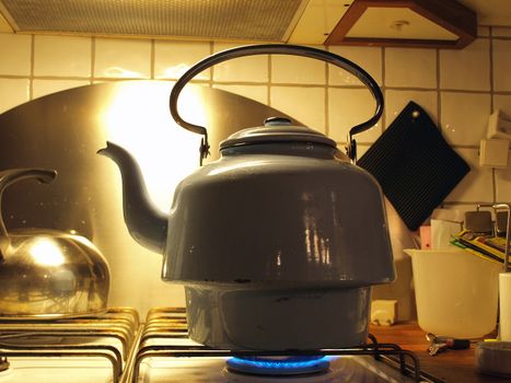 Kettle full of water boiling on a gas stove top