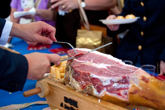 Waiter is slicing Italian raw ham