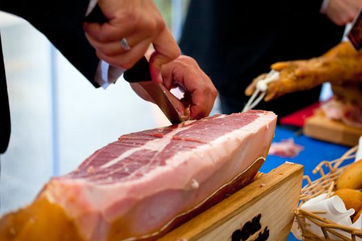 Waiter is slicing Italian raw ham