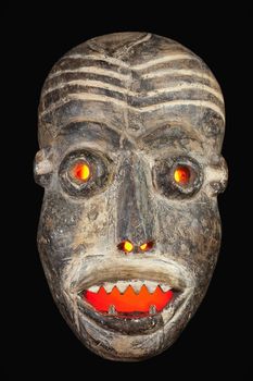 Wooden carved African tribal mask, dark wood with painted face. Isolated on black  background. Congo, Africa