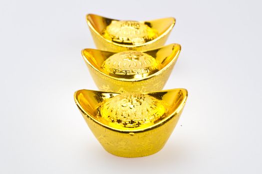 Three chinese gold ingots for new year celebration on white surface