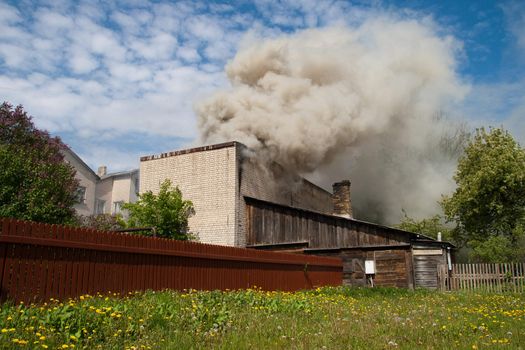 fire in city building, with white smoke to the blue sky