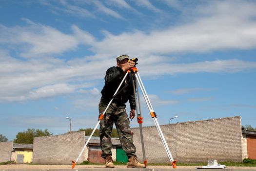 Surveyor measuring land for new street build.