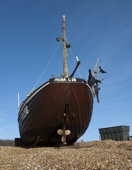 Brown fishing boat on the beach waiting to be towed to the sea