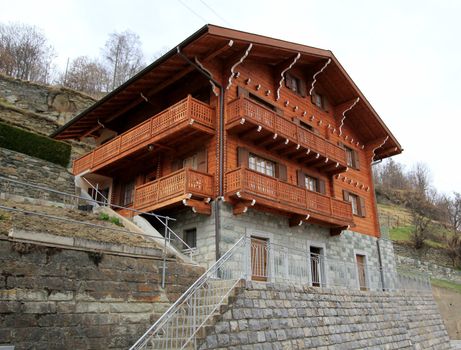 Brown wooden chalet in the mountain by winter cloudy day