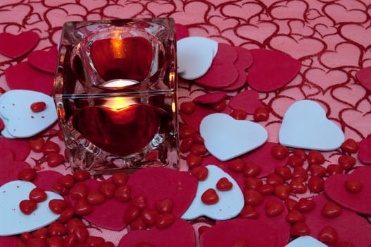 A background of material with hearts and hearts cut-outs and cinnamon candies