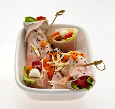 Appetizer with ham inside a saucer on a white background