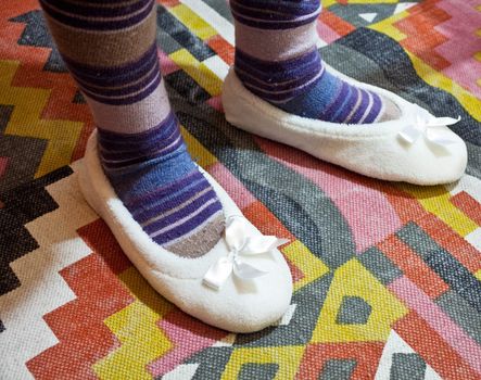 Female slippers on abstract carpet