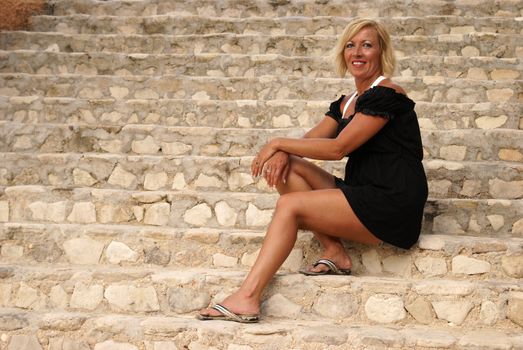 A woman in her forties sits on the staircase for a casual portrait.