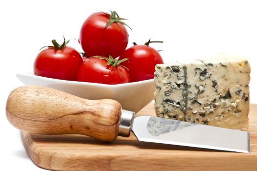 Chopping board with blue cheese and cherry tomatoes over white background