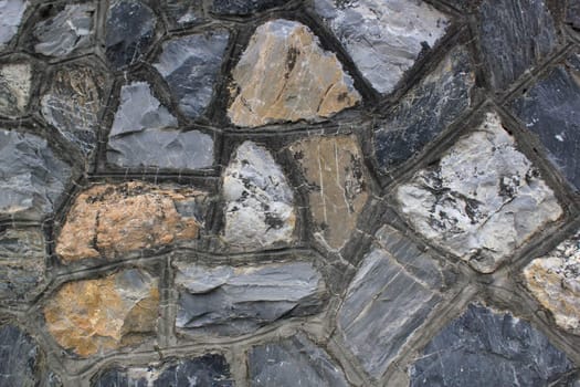 Close up of a grey wall made of different size rocks in the mountain