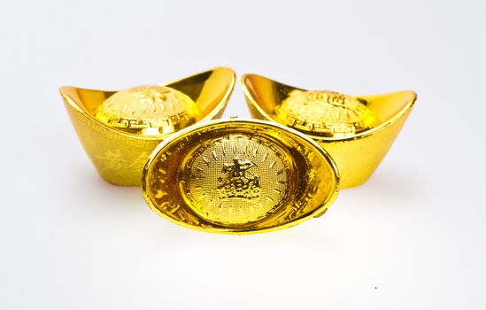 Three chinese gold ingots for new year celebration on white surface