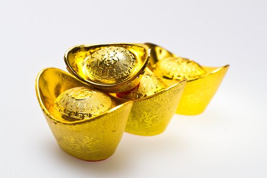 Chinese gold Ingots of various size line up on white surface