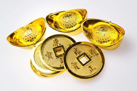 Gold ingots and Chinese Emperor's coin  on white surface