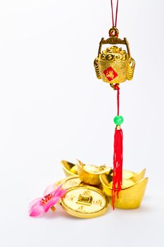 Hanging wealth pot pendant for Chinese New Year celebration with gold ingots and coins in background against white surface