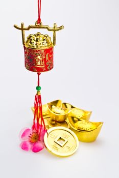 Hanging red wealth pot with gold igots and coins on white surface in portrait orientation