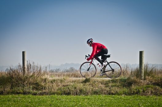 Man on road bike riding down open country road.