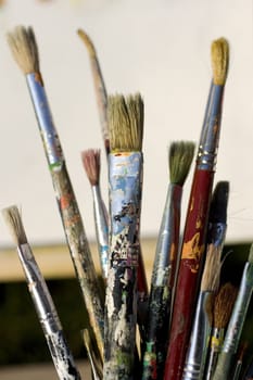 Paintbrushes and painted canvas in the background