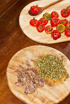 Red hot chili peppers on cutting board, capers and anchovies