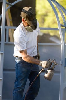 Construction steel worker uses a paint sprayer to apply a primer coat to metalwork.