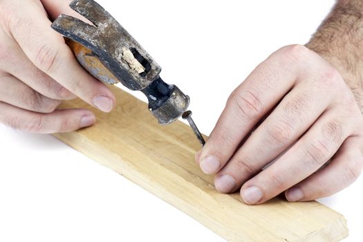 Man's hands hitting a nail on the head with old and used wood hammer on white background.