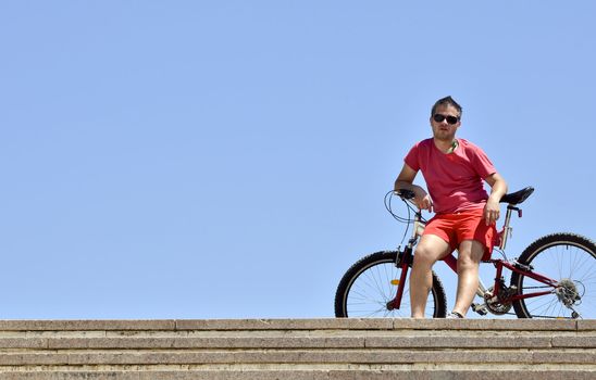Young man on bicycle against a blue sky