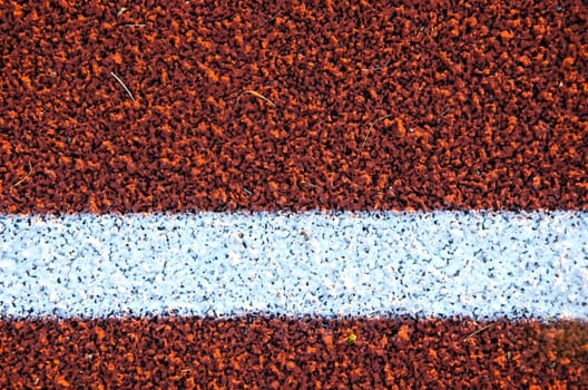 Stadium running track surface closeup background. Interesting textures.