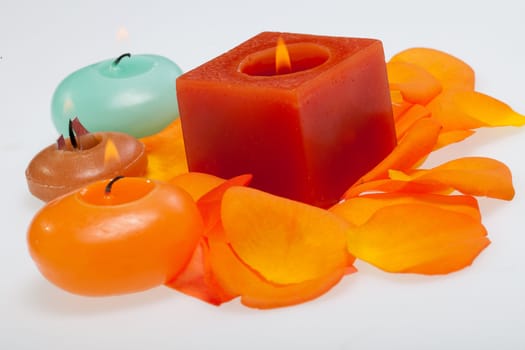 Spilt petals of the orange-rose around the aromatic candle