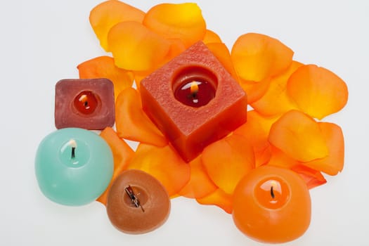Spilt petals of the orange-rose around the aromatic candle