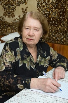 The elderly woman writes the letter